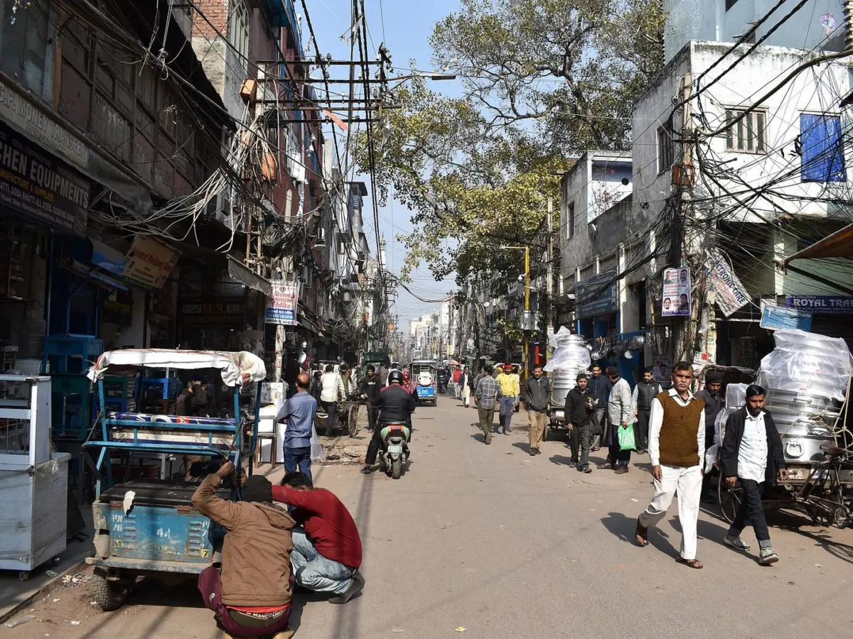 A wide bazaar street in Old Delhi with handcarts, rickshaws and shops on both sides