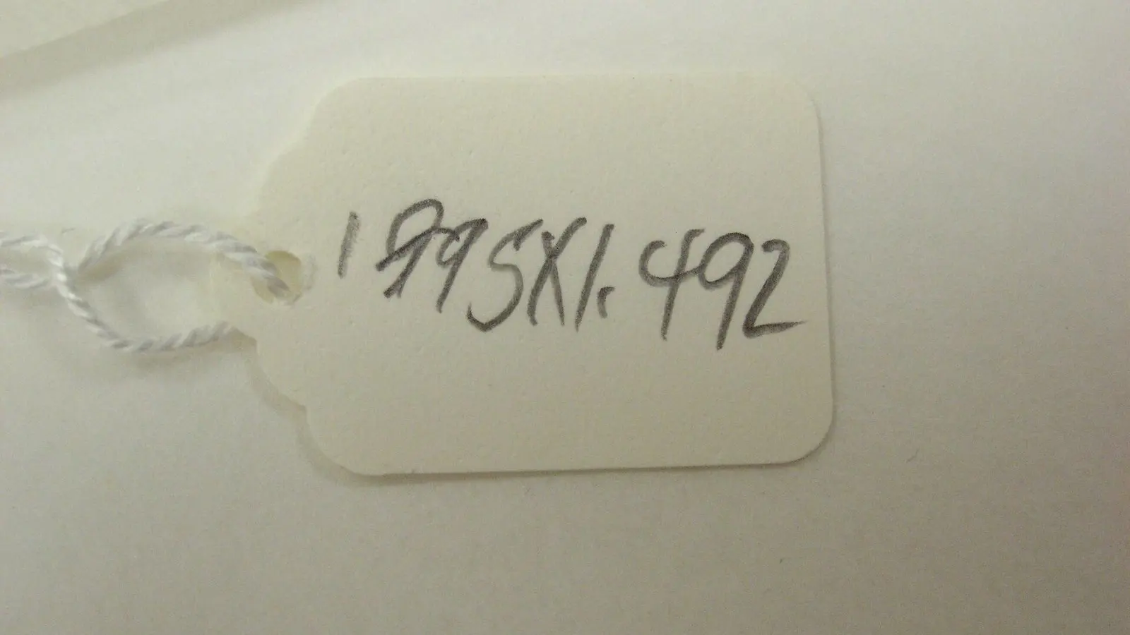 A paper tag with a handwritten number tied to a bolt of yellow fabric