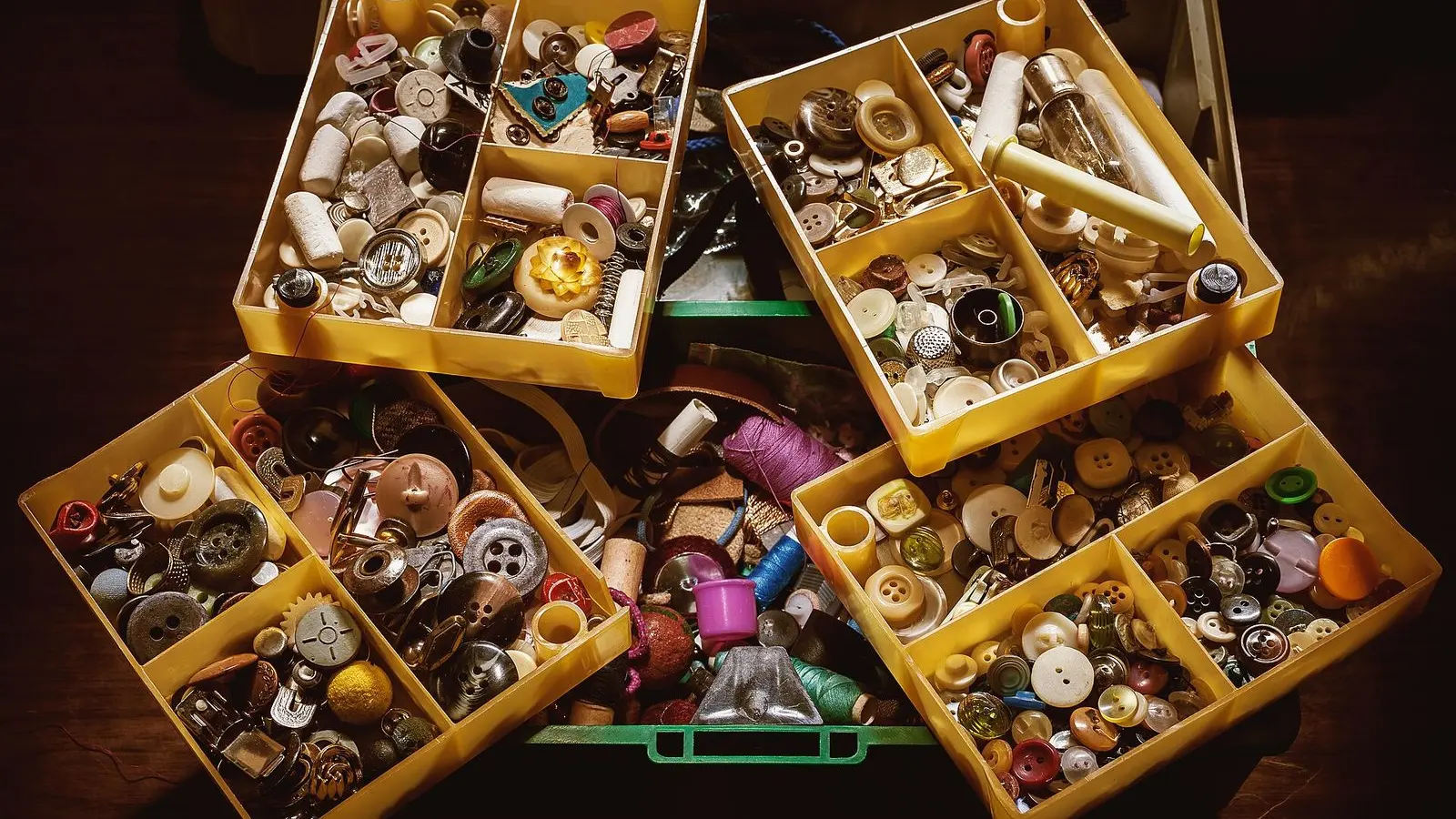 An open sewing box with compartments full of buttons in many colours, sizes and materials