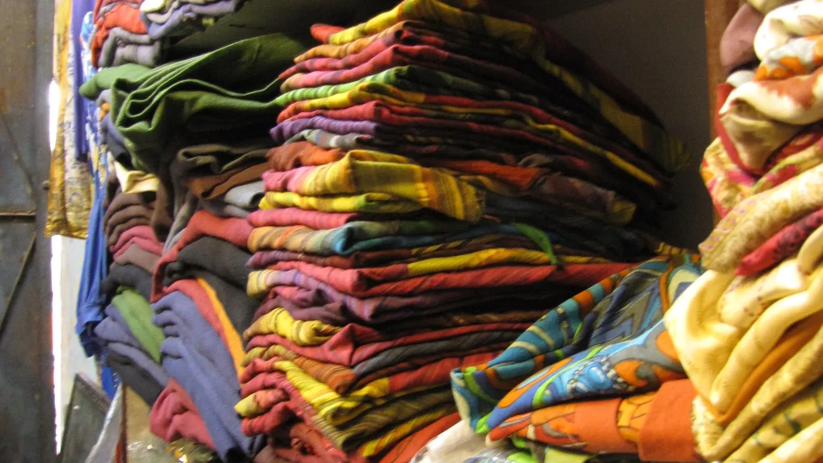 Stacks of folded printed garments on the shelves of a clothes shop in Paharganj, Delhi