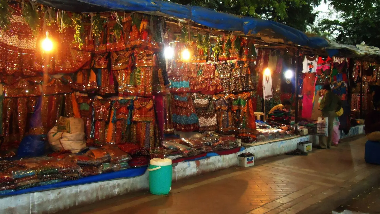 A row of stalls hung with embroidered chaniya cholis, lit at dusk near Law Garden, Ahmedabad
