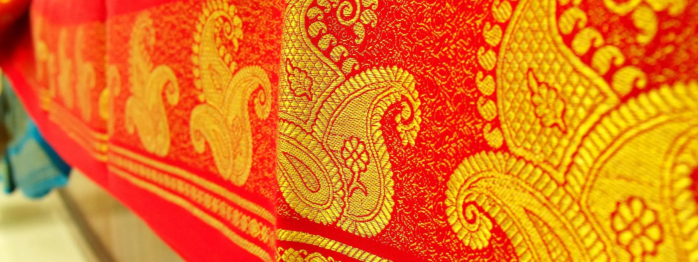 Close view of a red Mysore silk saree with a broad border of gold zari paisleys