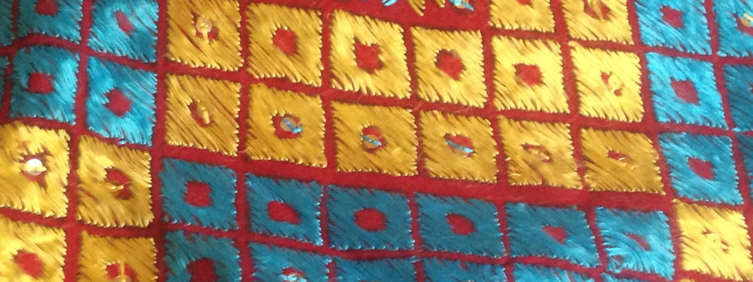 A hand-embroidered phulkari dupatta from Patiala in gold, saffron and teal silk floss on red cloth