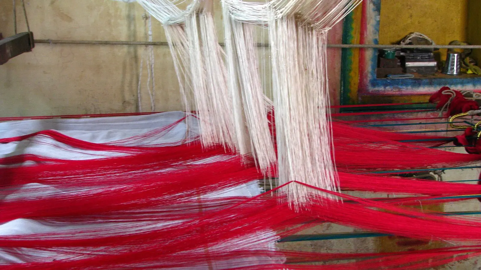 Red and white silk threads stretched on a hand loom for weaving a saree in Kanchipuram