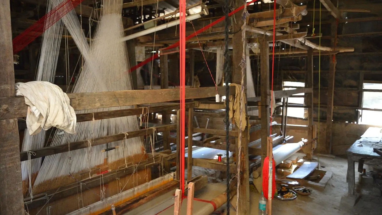 Wooden handlooms with warp threads set up inside a weaving shed in Phulia, Nadia
