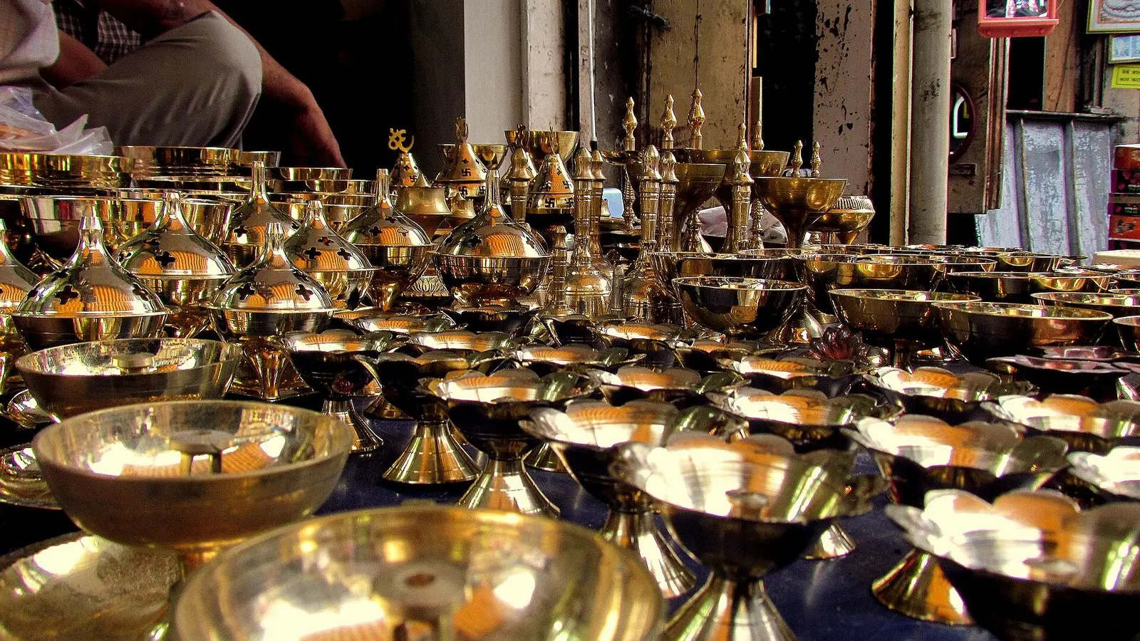 Brass lamps and diyas stacked for sale on a stall in Tulshibaug market, Pune
