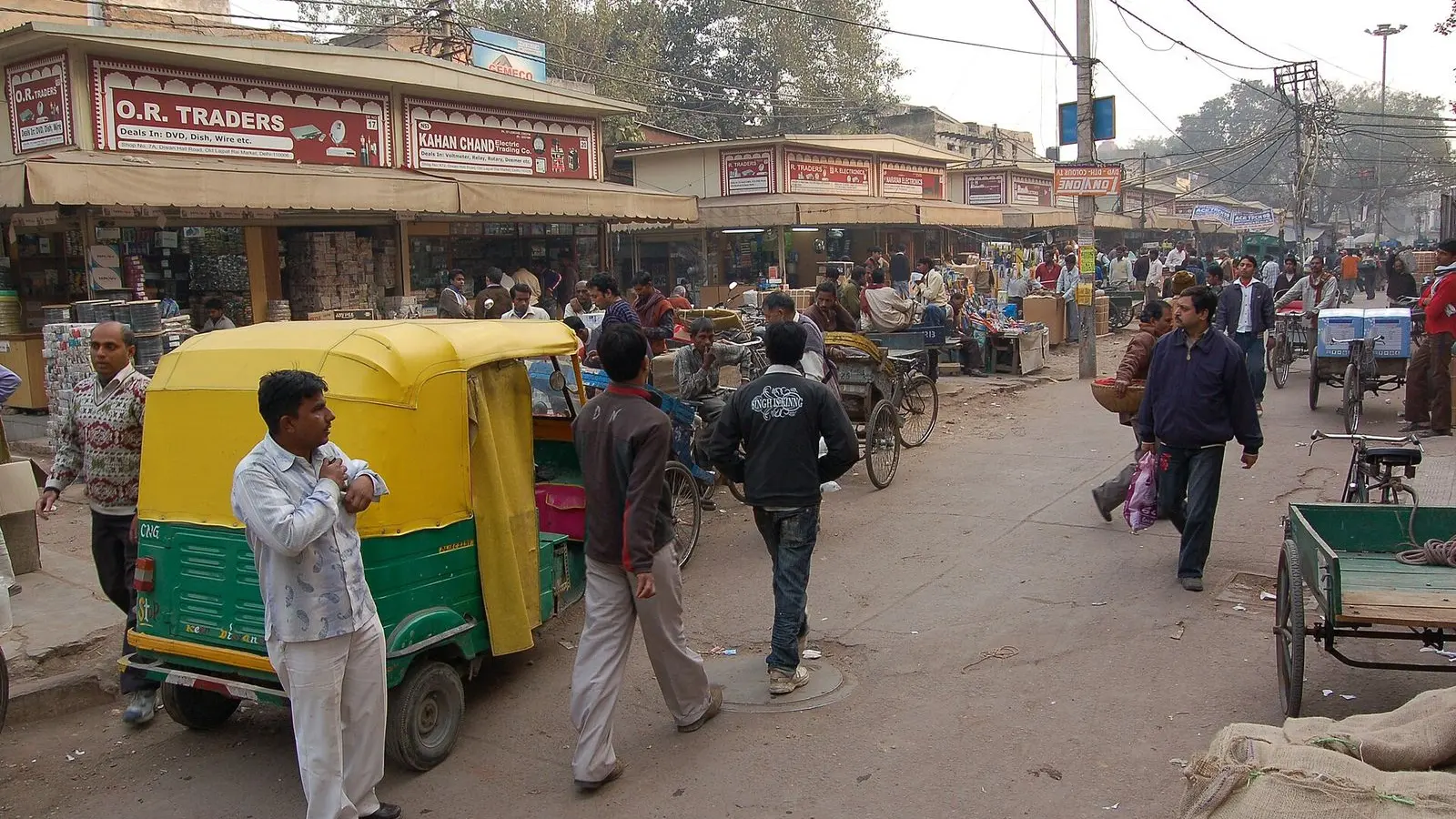 A busy street in Chandni Chowk, Delhi, with an auto rickshaw, handcarts and people carrying goods