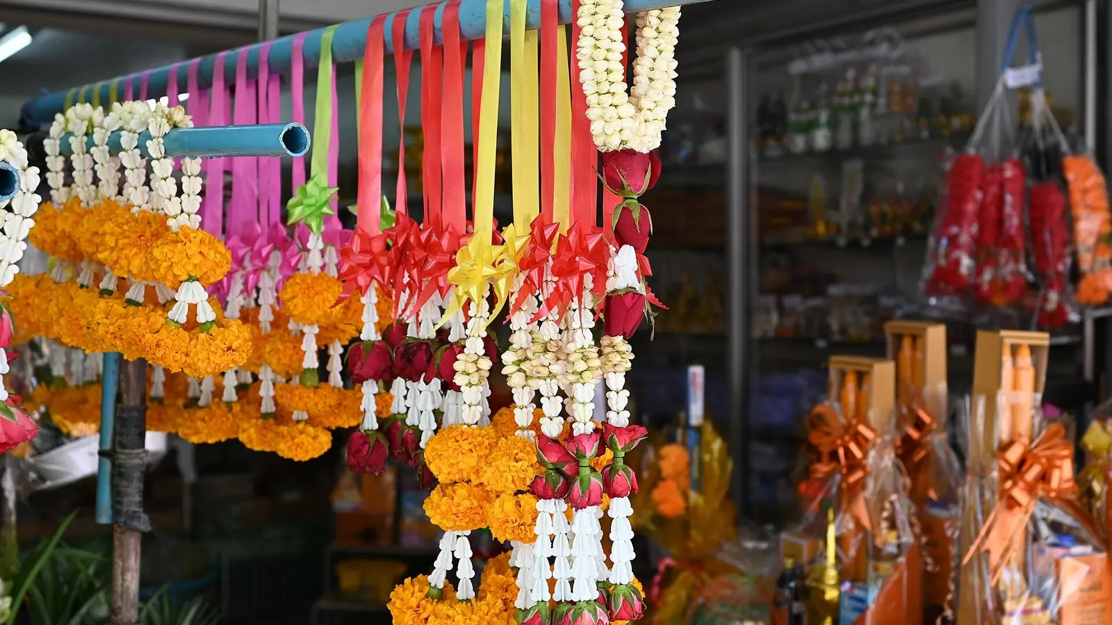 Marigold garlands and bright ribbons hanging above a market stall