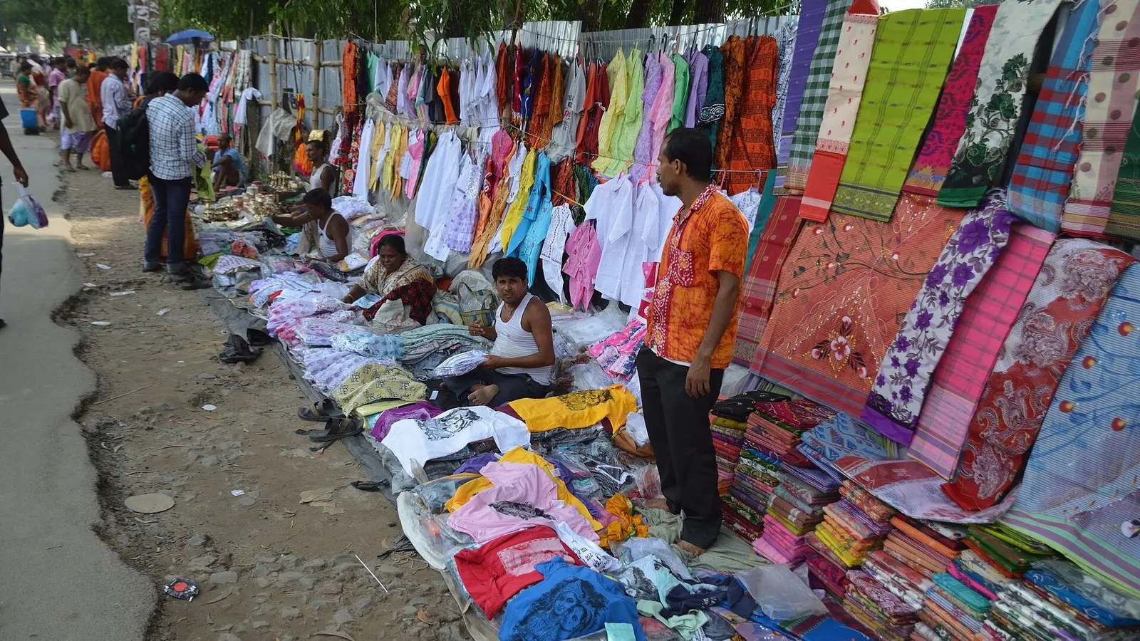 Rows of garments laid out and hung for sale at open-air stalls in Mayapur, West Bengal
