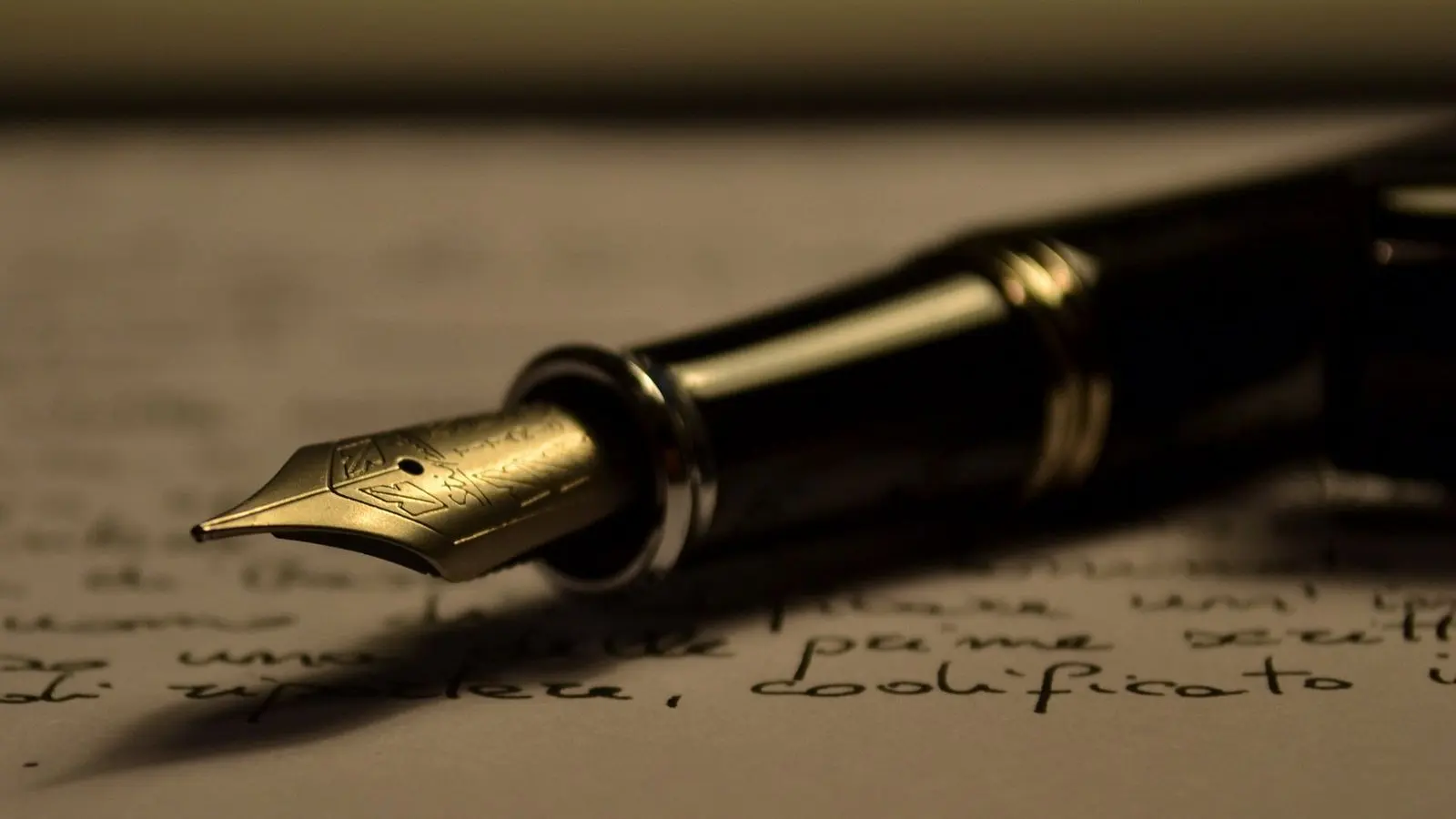 A fountain pen lying on a handwritten page in warm, low side light