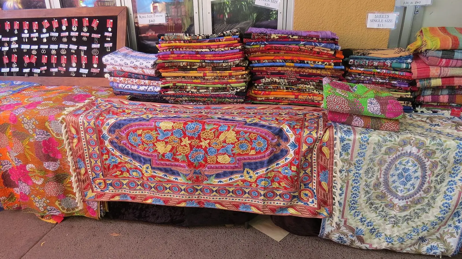 Folded bedspreads in bright printed cotton piled high on a market stall table