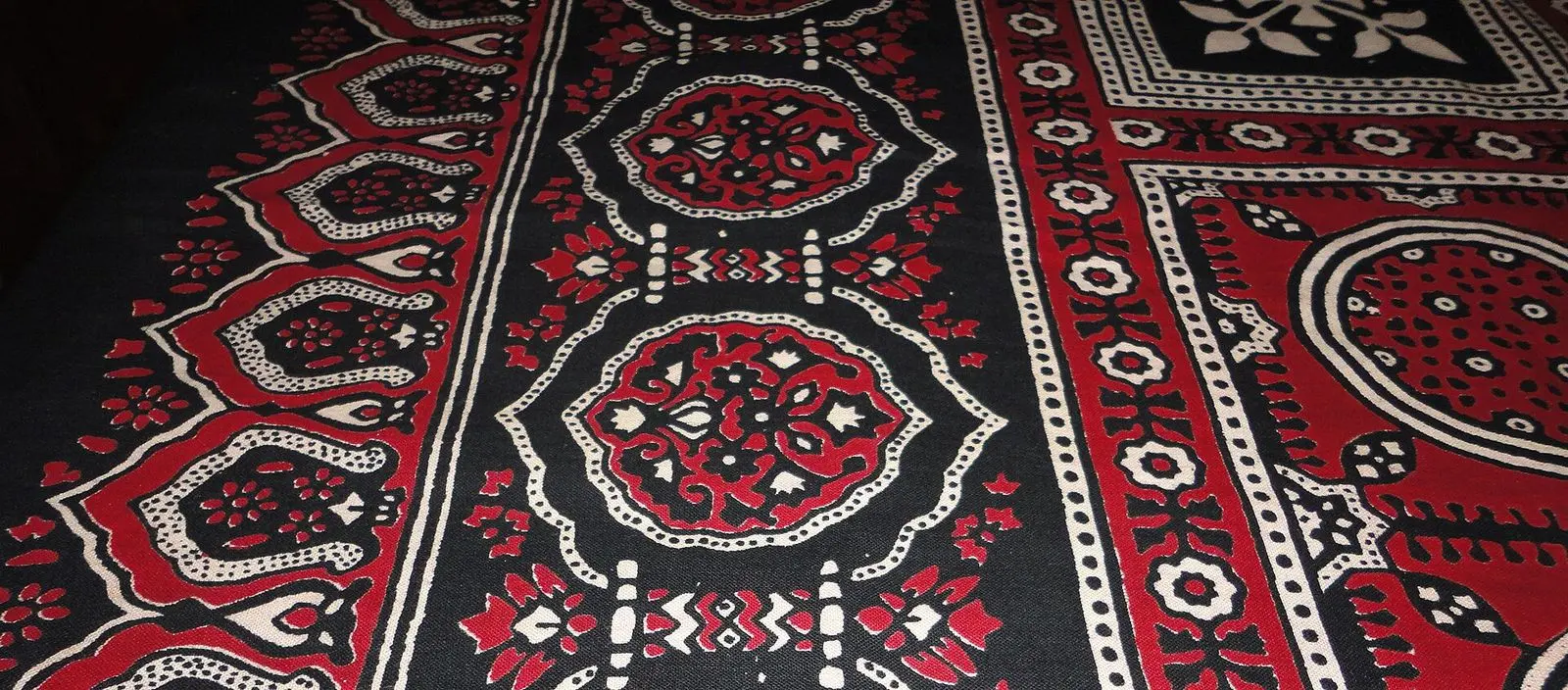 Ajrak block-printed cotton in deep red, black and white, spread flat and seen close