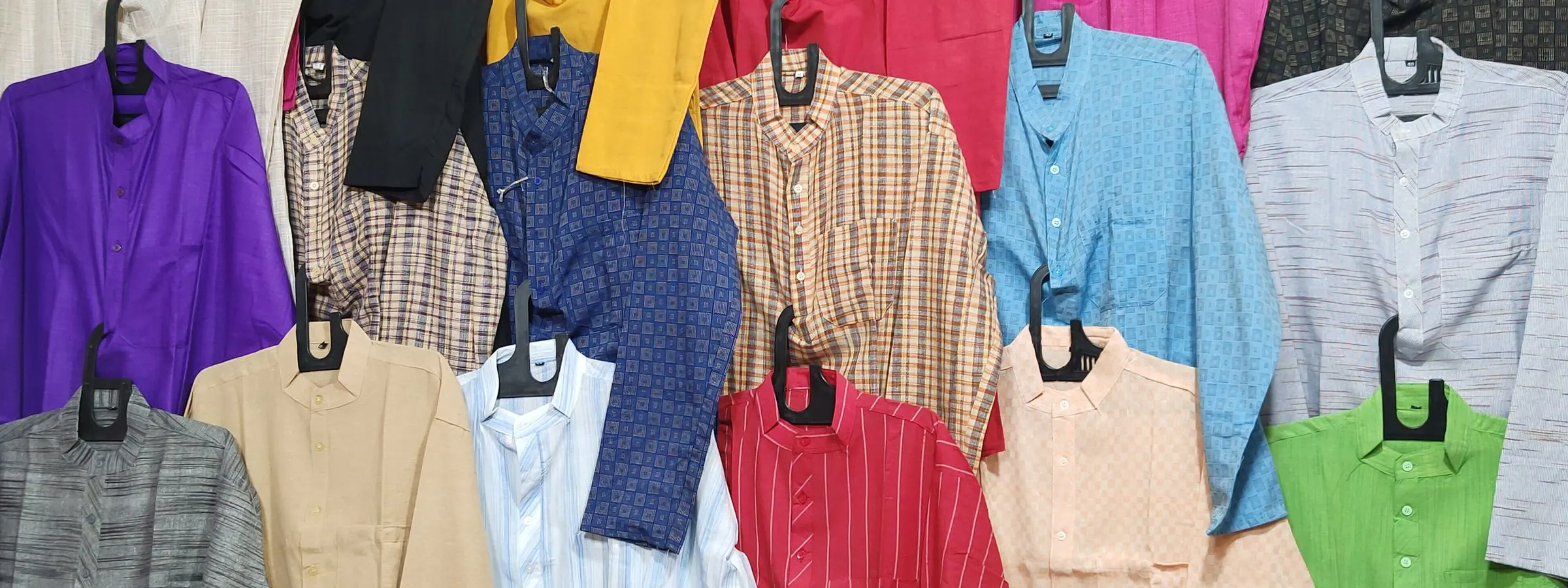Kurtas in pink, yellow, blue and cream hung in rows on a clothing rail