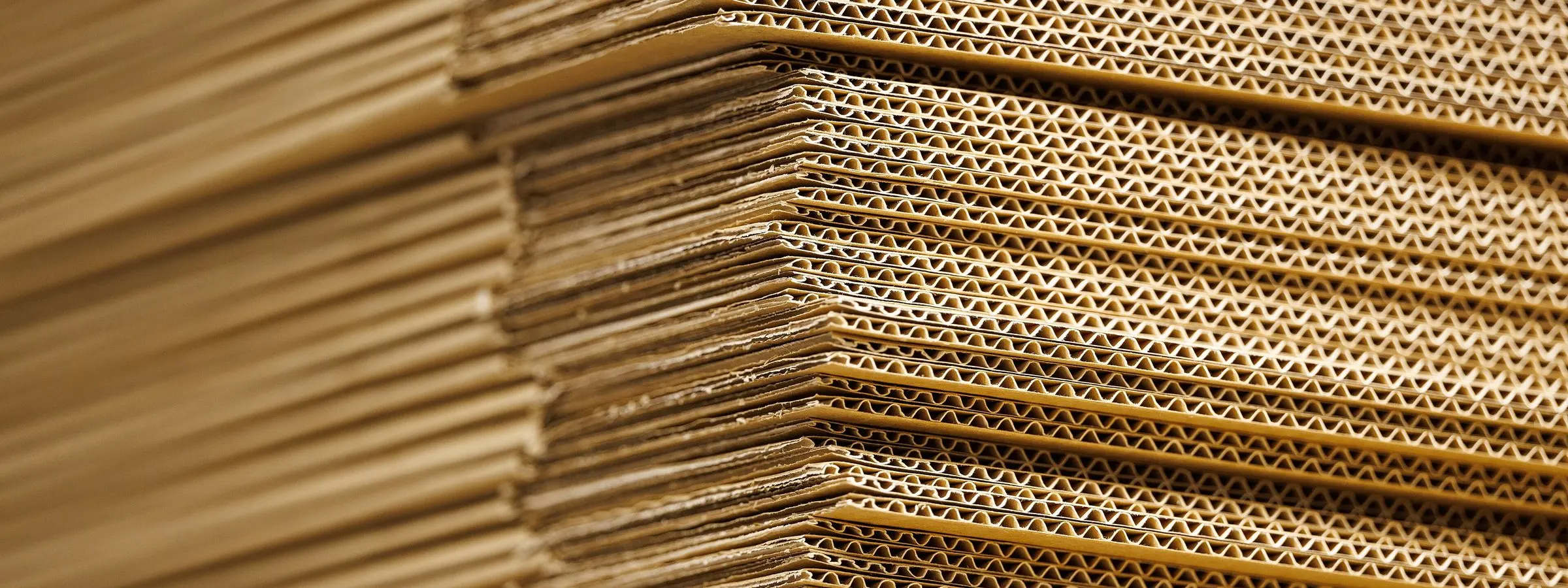 Close view of flattened corrugated cardboard sheets stacked edge to edge
