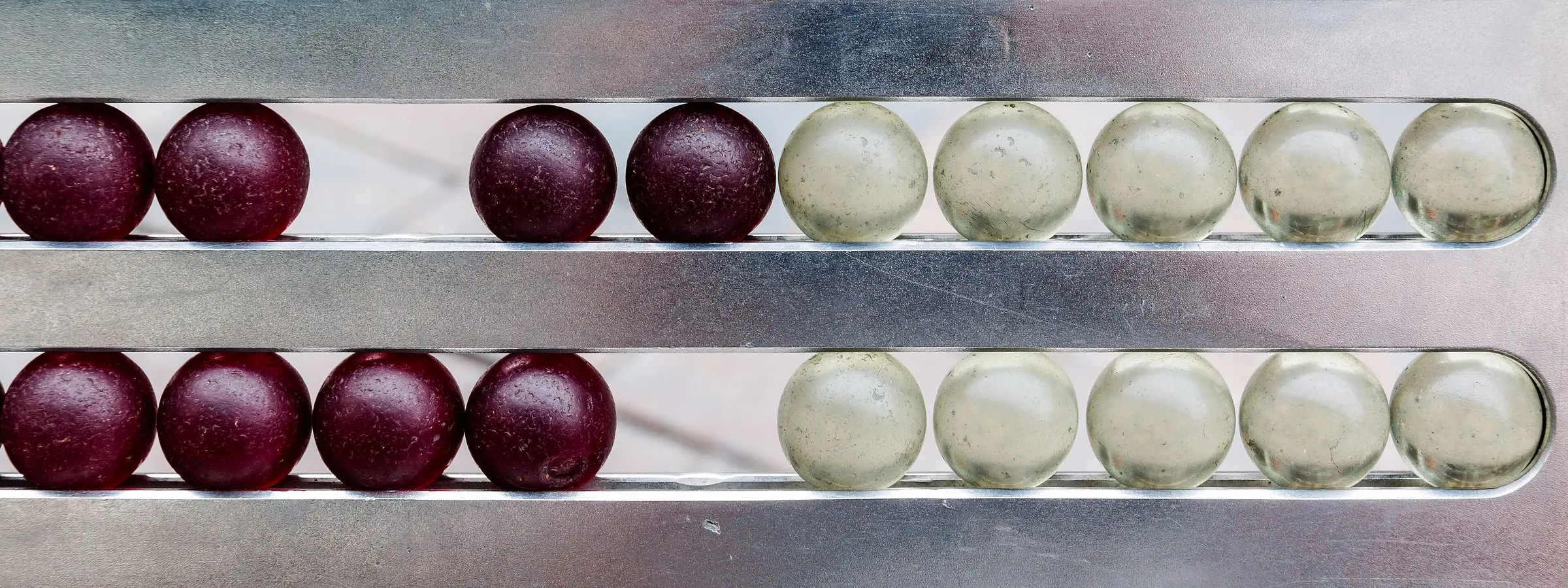 Close view of red and cream abacus beads on metal rods, counted to one side