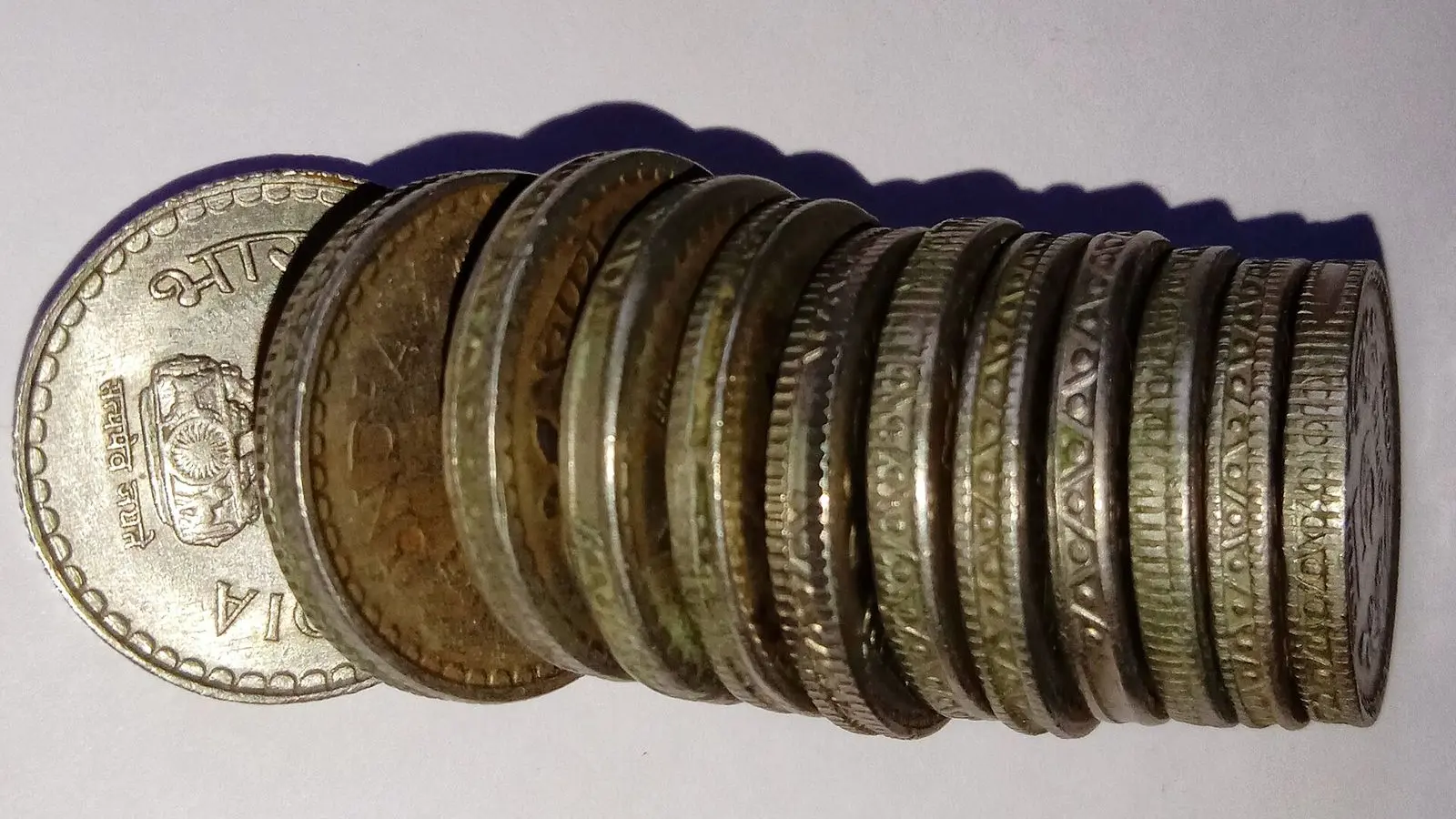 A row of Indian five rupee coins stacked on edge, their milled rims in close focus