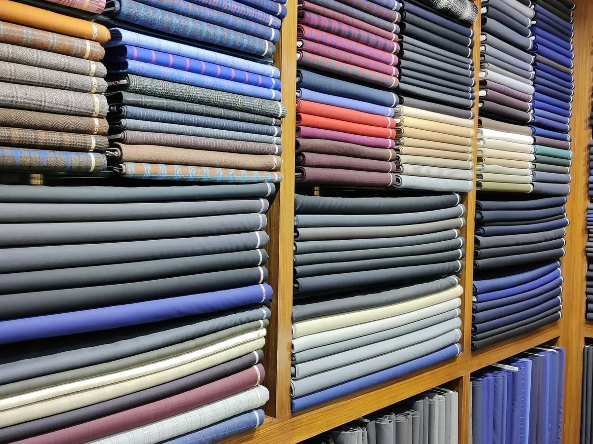 Shelves of folded cloth in blues, greys and browns stacked high in a cloth shop