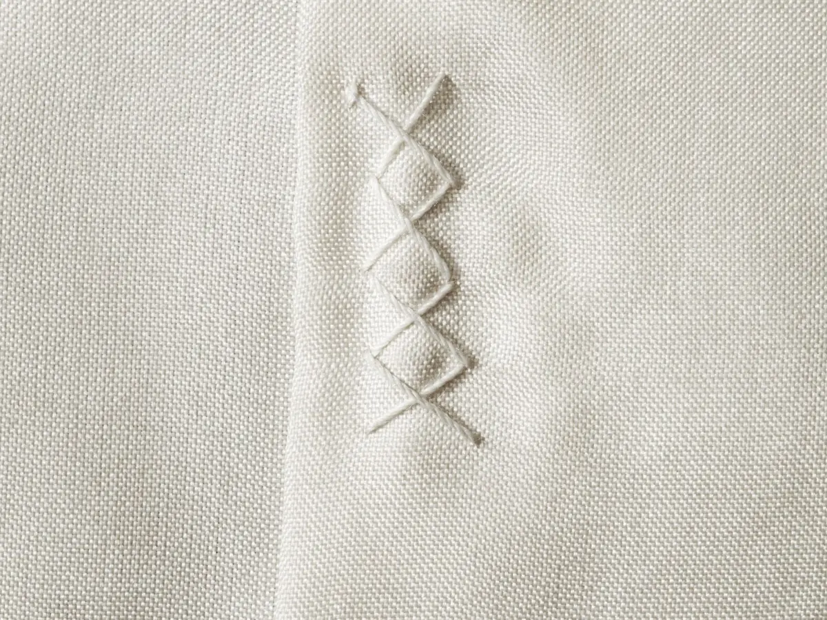 Close view of white cotton fabric with a short line of decorative stitching