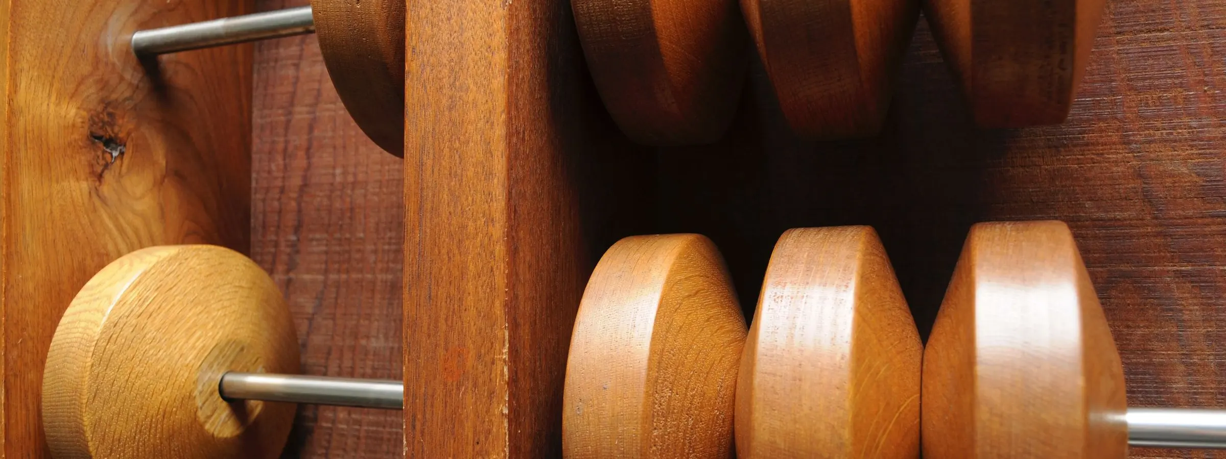 Close view of large wooden abacus beads on steel rods beside a wooden frame